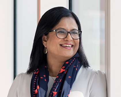 Posed image of Shobie wearing glasses and a navy blue scarf