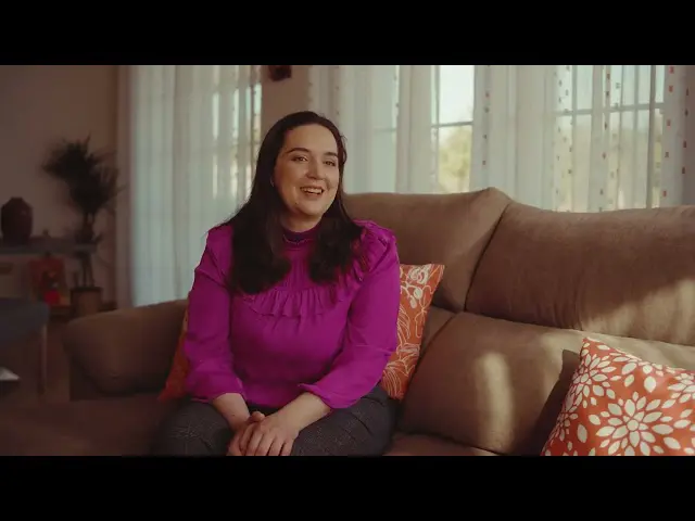 smiling woman in a pink shirt sitting on a couch