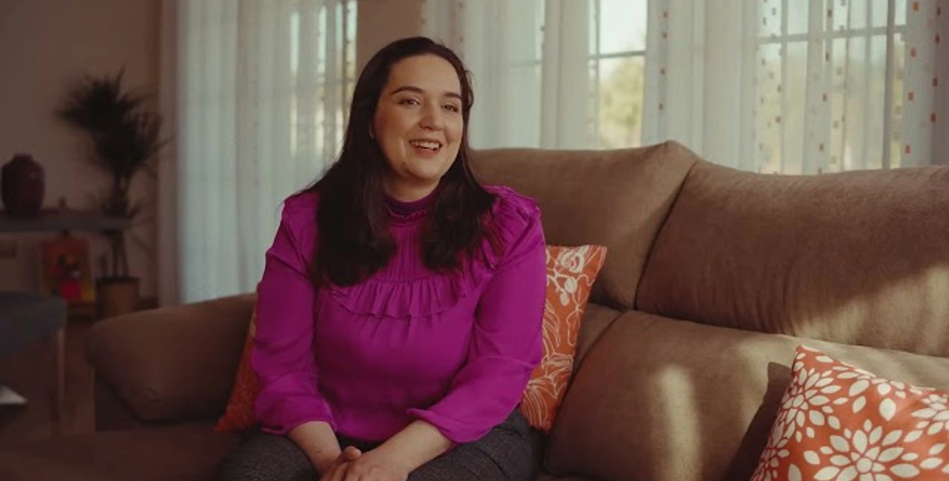 smiling woman in a pink shirt sitting on a couch