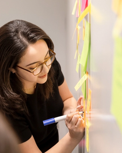 Woman writing notes on a whiteboard while other employees watch