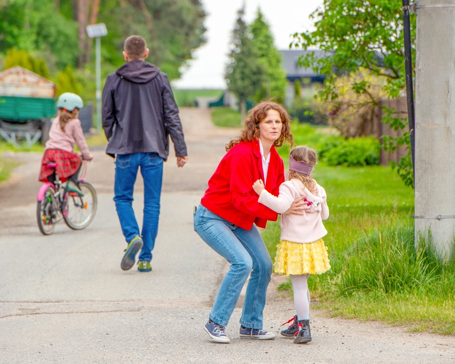Natalia carrying her daughter with her husband and other daughter walking in the background