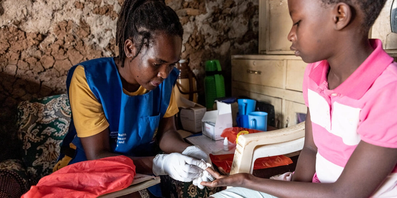 Community healthworker testing child for malaria