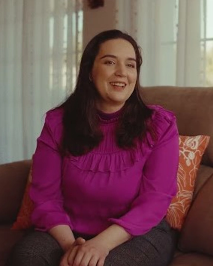 Angeles sitting on a sofa in a pink shirt