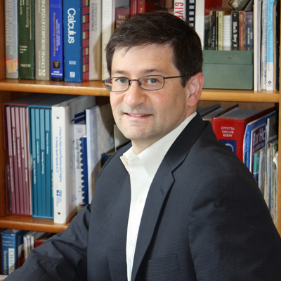 Man in suit sitting in front of bookshelf