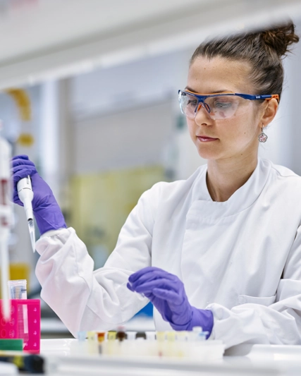 Woman in lab coat using a syringe