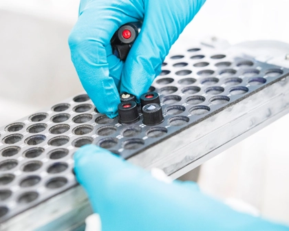 scientist with blue gloves placing testing tubes on a rack