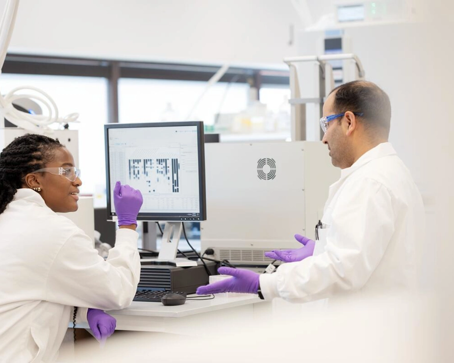 two scientists collaborating at computer in lab