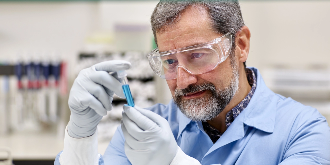 Lab worker examining a blue vial
