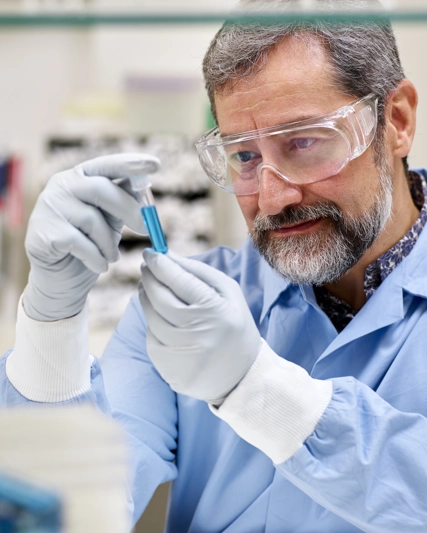 Lab worker examining a blue vial