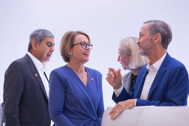 CFO Julie Brown talks to Board Director Charles Bancroft, behind stands Vishal Sikka, Liz Anderson